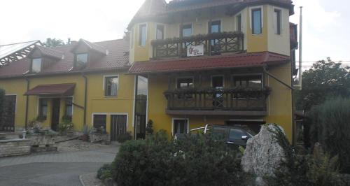 Una casa amarilla con un balcón en el lateral. en Dudás panzió, en Bükkszentkereszt