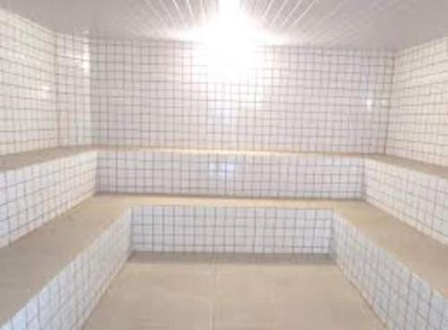 um quarto com paredes de azulejos brancos e uma luz em Catarina Chalé - Cond Clube em Mairinque