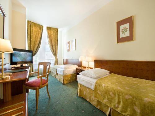 a hotel room with two beds and a desk at EA Hotel Rokoko in Prague