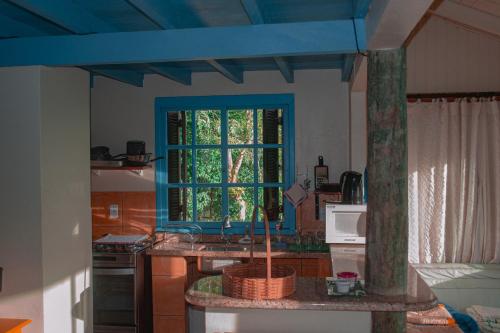 eine Küche mit einem Waschbecken und einem blauen Fenster in der Unterkunft Doce Cabana Pousada in Barra de Ibiraquera