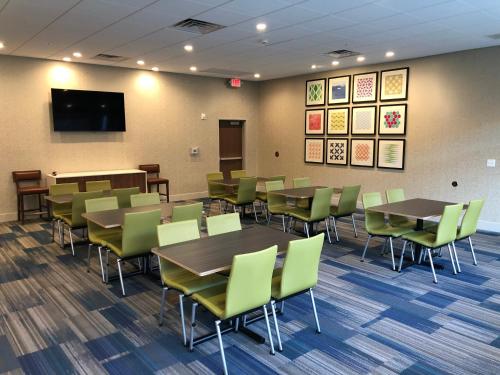 a waiting room with tables and chairs and a flat screen tv at Holiday Inn Express & Suites - Madison West - Middleton by IHG in Middleton