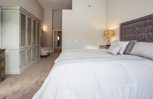 a white bedroom with a large white bed and a chair at Snowcreek #754 - Phase V in Mammoth Lakes