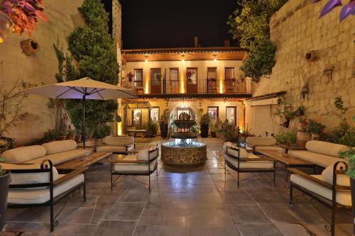 eine Terrasse mit Tischen, Stühlen und einem Brunnen in der Unterkunft Aja Cappadocia Cave Hotel in Ürgüp