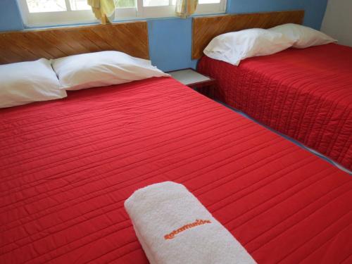 2 camas con edredón rojo y toalla en Hotel Albri by Rotamundos en Tecolutla