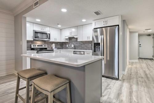a kitchen with white cabinets and a stainless steel refrigerator at Coastal Orange Beach Condo Resort and Beach Access! in Orange Beach