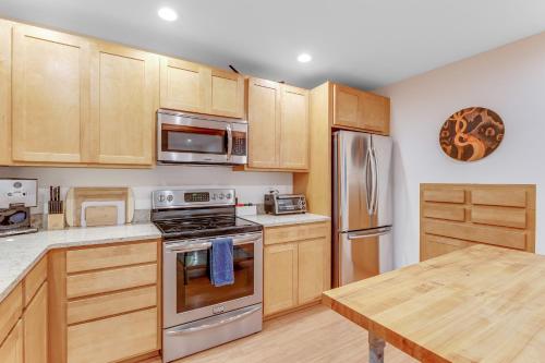 a kitchen with wooden cabinets and stainless steel appliances at McKinnis Hill Cabin in Eastsound