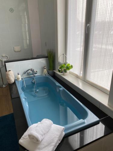La salle de bains est pourvue d'une baignoire bleue et de serviettes. dans l'établissement Vakantiehuis Ormille-aan-zee, à Knokke-Heist