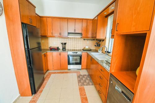 a kitchen with wooden cabinets and a stainless steel refrigerator at Aloe Villa Chania Crete in Georgioupolis