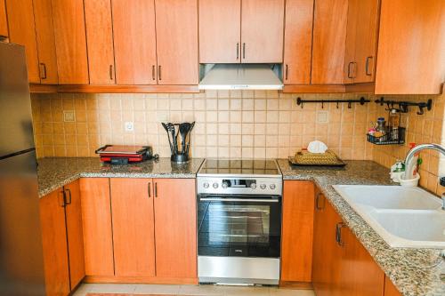 a kitchen with wooden cabinets and a stove and a sink at Aloe Villa Chania Crete in Georgioupolis
