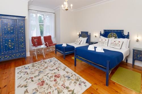 two beds in a room with blue furniture and a rug at Quinta Das Murtas B&B in Sintra