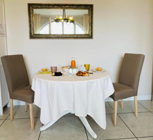 a table with a white table cloth and two chairs at La Rosa Gialla Bio Apartments & rooms in Barolo