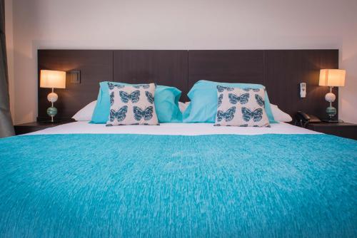 a bedroom with a large bed with blue sheets and pillows at Soho Luxury Suites in Buenos Aires