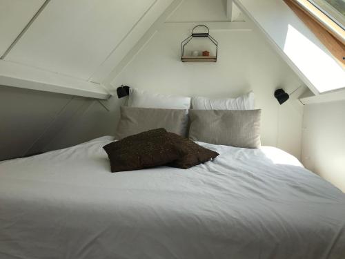 un letto bianco con un cuscino sopra di B&B De Jagthut a Driel