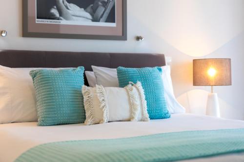 a bedroom with a bed with blue and white pillows at Century Park in Nelson