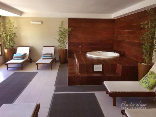 a room with a bath tub and two chairs at Belíssimo Apartamento Centro de Itaipava All Suites in Itaipava