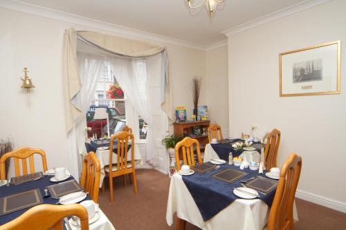 a dining room with two tables and chairs at Cunard Guest House in Weymouth