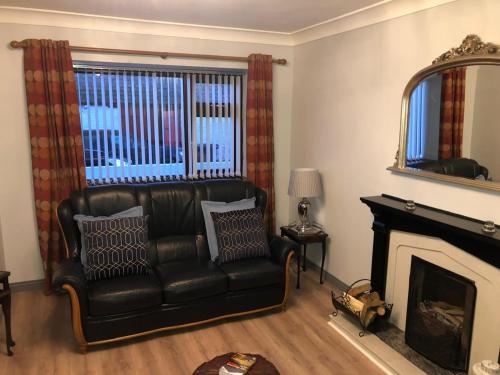 a living room with a leather couch and a fireplace at Littles Cottage, heart of the Mournes in Annalong