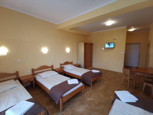a room with four beds and a tv in it at Dom Wypoczynkowy Pod Taborem in Niedzica Zamek