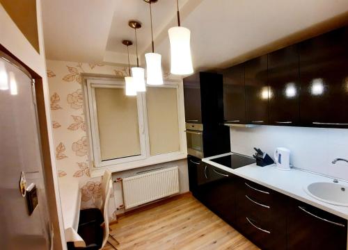 eine Küche mit Holzschränken, einem Waschbecken und einem Spiegel in der Unterkunft M&M Apartment VIII Self CHECK-IN in Panevėžys