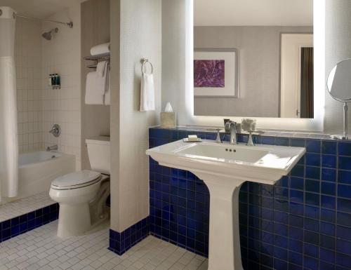 a blue tiled bathroom with a sink and a toilet at The Ashton Hotel in Fort Worth