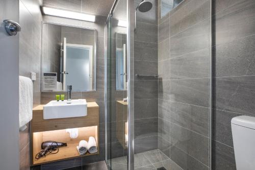 a bathroom with a shower and a sink and a toilet at Nightcap at Skyways Hotel in Melbourne