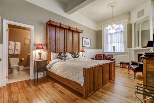 - une chambre avec un grand lit et une tête de lit en bois dans l'établissement School House Bed and Breakfast C.1859, à Niagara on the Lake