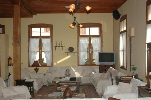 a living room with white couches and a tv at Hotel Koukouli in Souflíon