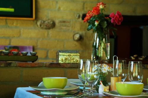a table with wine glasses and a vase with flowers at Posada la Serena in Villa de Leyva