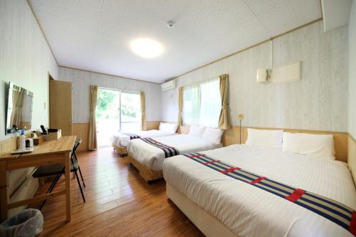 沖縄市にあるグリーンガーデンヒルズ 3F-2のベッド2台とデスクが備わるホテルルームです。