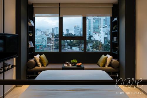 ein Schlafzimmer mit einem Bett und einem großen Fenster in der Unterkunft Bare Chic - Bare Boutique Stays in Ho-Chi-Minh-Stadt