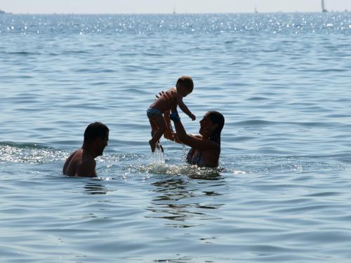two men and a child playing in the water at Aptos. Comte D´Empuries in Empuriabrava