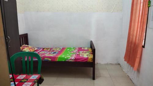 a small room with a bed and a chair at Yellow House in Sunggal