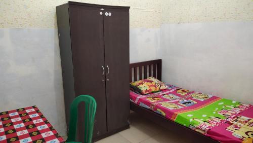 a bedroom with a bed and a wooden cabinet next to a bed at Yellow House in Sunggal