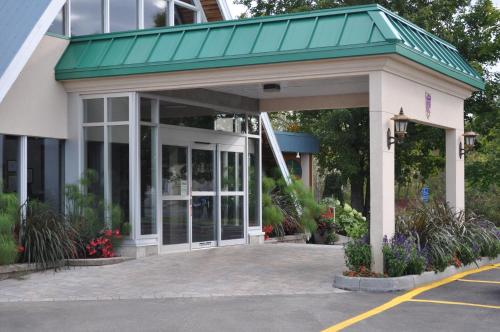 a store front with a green roof and flowers at Hôtel Le Francis in New Richmond
