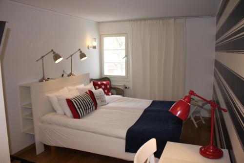 a bedroom with a bed with red lamps and a desk at Jennys Hotell och Restaurang in Arvika