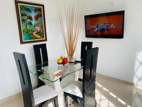 a glass dining room table with two white chairs at Finca Villa Maju in Papagalleros