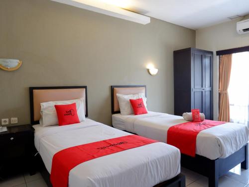 two beds in a hotel room with red pillows at RedDoorz At Jalan Sriwijaya Semarang in Semarang