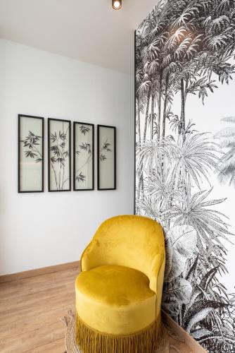 a yellow chair in a room with a wall at Le Cocon Des Artistes in Lyon