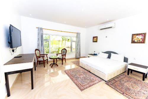 a bedroom with a bed and a desk and a television at Oriental Nights Rest House in Al Wāşil