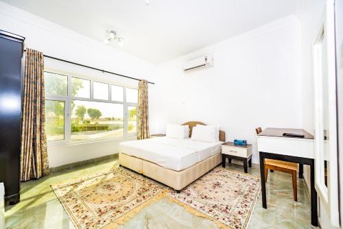 a white bedroom with a bed and a desk at Oriental Nights Rest House in Al Wāşil