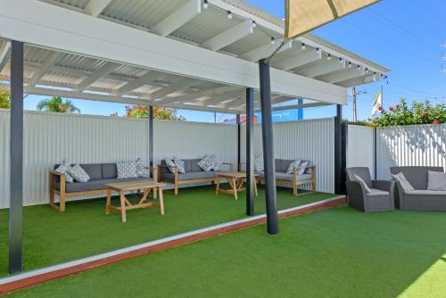 a pergola with couches and tables on a lawn at Discovery Parks - Adelaide Beachfront in Adelaide