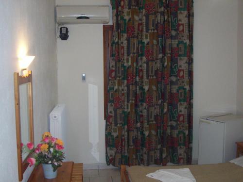 a room with a shower curtain and a bed with flowers at Hotel Elytis in Potistika