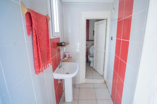 La salle de bains est pourvue d'un lavabo et d'une serviette rouge. dans l'établissement Lotus Garden Hostel Izmir, à Izmir