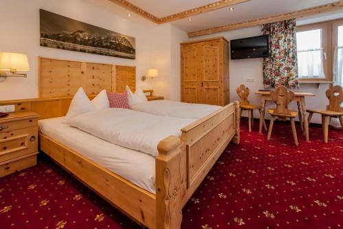 a bedroom with a large bed and a table at Kaiserhotel Kitzbühler Alpen in Oberndorf in Tirol