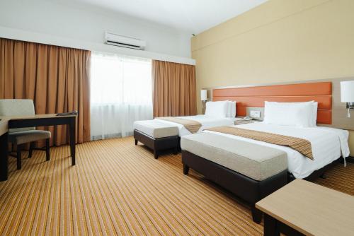 um quarto de hotel com duas camas e uma secretária em Raia Hotel & Convention Centre Terengganu em Kuala Terengganu