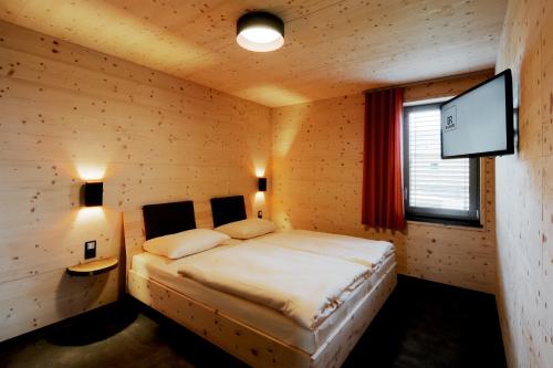 - une chambre avec un lit et une télévision à écran plat dans l'établissement MANOAH- Häuser am See, à Zeulenroda-Triebes