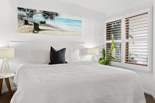 a white bedroom with a bed and a window at Sea Salt - Lennox Head in Lennox Head