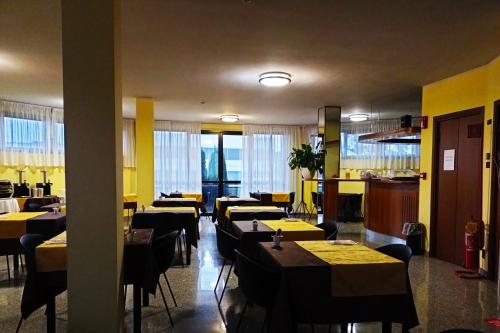 restauracja ze stołami i krzesłami z żółtymi ścianami w obiekcie Hotel Motel Europa w mieście Ossona