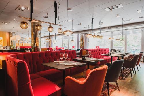 a restaurant with red booths and tables and chairs at Hotel Rival in Stockholm