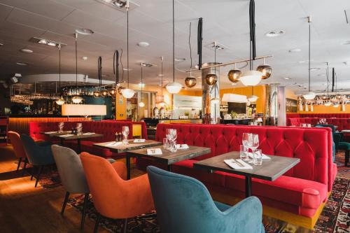 a restaurant with a red couch and tables and chairs at Hotel Rival in Stockholm